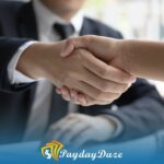 Two people shaking hands over a table after learning how to geta payday loan in someone else's name