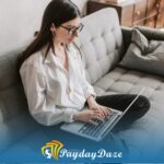 A woman sitting on a couch using a laptop computer to obtain a payday loan with no job verification